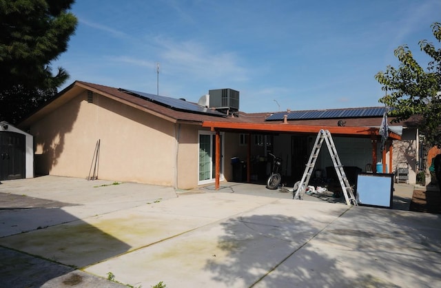 back of house with central AC, a shed, and solar panels