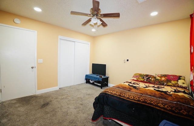 carpeted bedroom with ceiling fan, a closet, and a textured ceiling