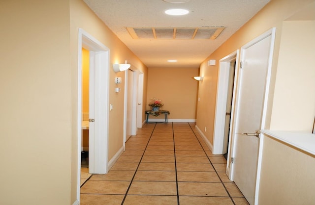 hall with a textured ceiling and light tile patterned floors