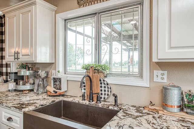 kitchen featuring white cabinetry, light stone countertops, and sink