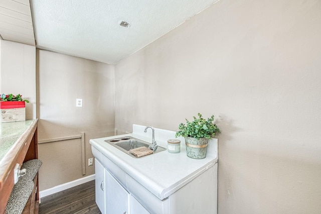 laundry area featuring dark hardwood / wood-style floors, sink, and a textured ceiling