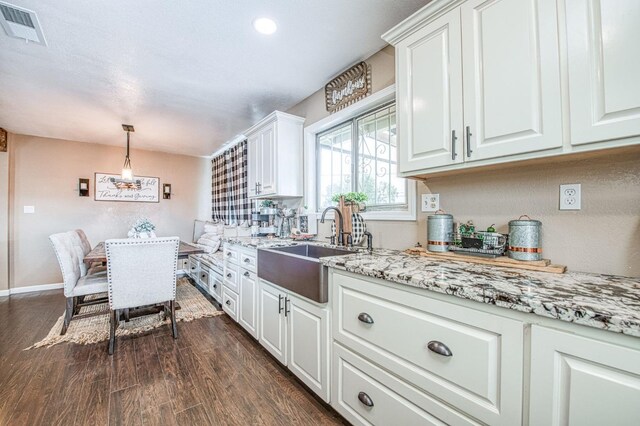 kitchen with decorative light fixtures, white cabinetry, sink, dark hardwood / wood-style flooring, and light stone counters