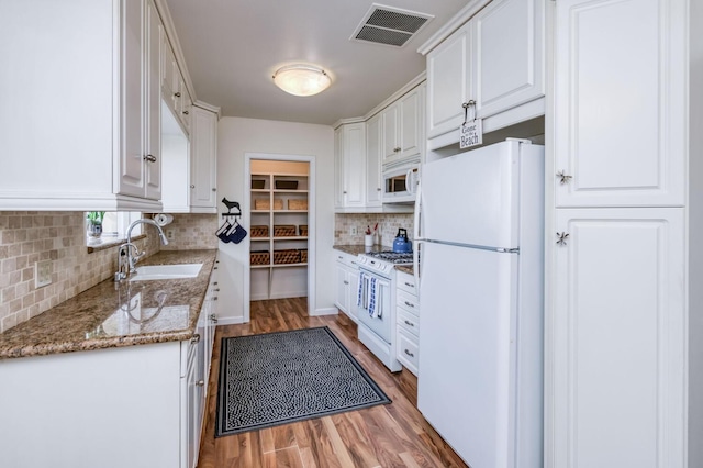 kitchen with tasteful backsplash, a sink, white appliances, white cabinetry, and visible vents