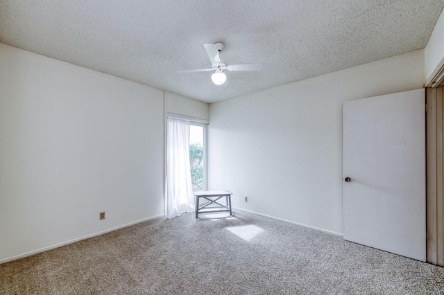 spare room with ceiling fan, baseboards, a textured ceiling, and carpet