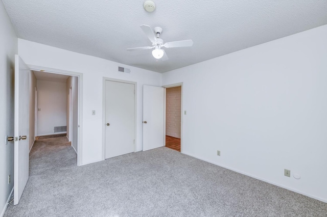 unfurnished bedroom with carpet floors, visible vents, and a ceiling fan