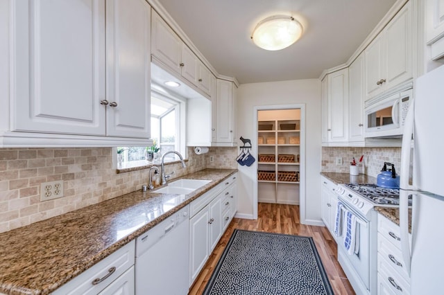 kitchen with white cabinets, white appliances, a sink, and light wood-type flooring