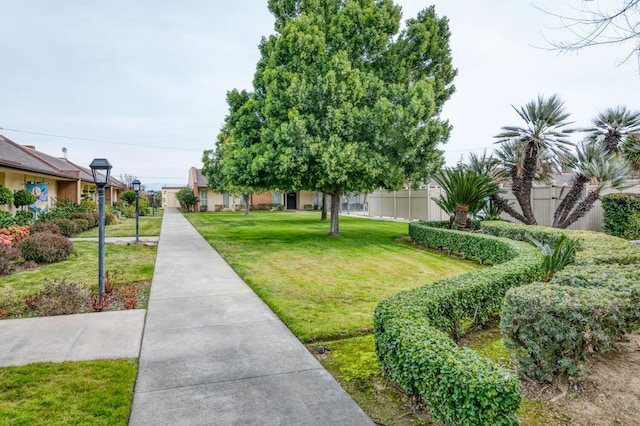 view of community featuring a lawn and fence