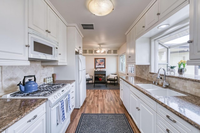 kitchen with visible vents, white cabinetry, a sink, and white appliances