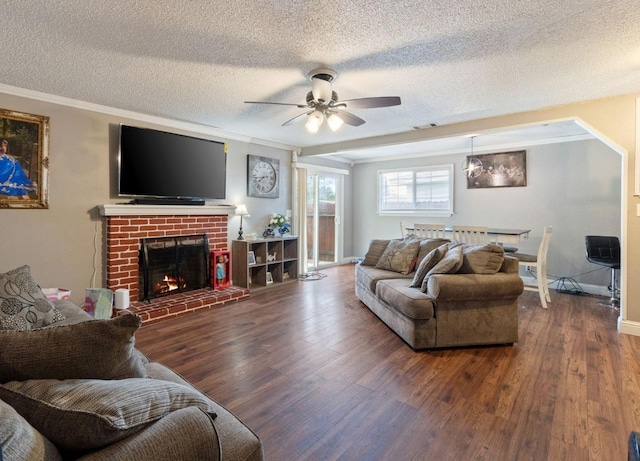 living room featuring a textured ceiling, ceiling fan, crown molding, dark hardwood / wood-style flooring, and a fireplace