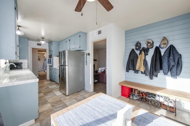 mudroom featuring ceiling fan, sink, and wood walls