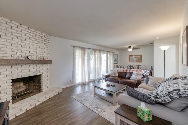 living room featuring ceiling fan, dark wood-type flooring, and a brick fireplace