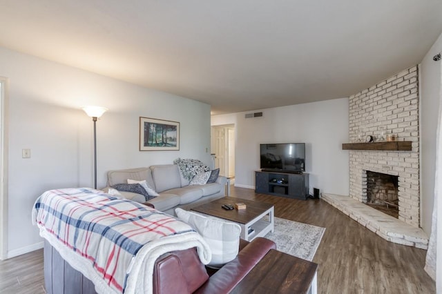 living room featuring a brick fireplace and wood-type flooring