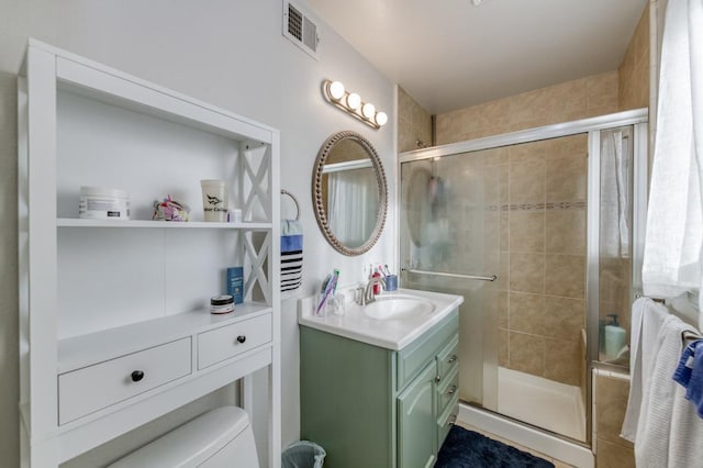 bathroom with toilet, a shower with shower door, and vanity