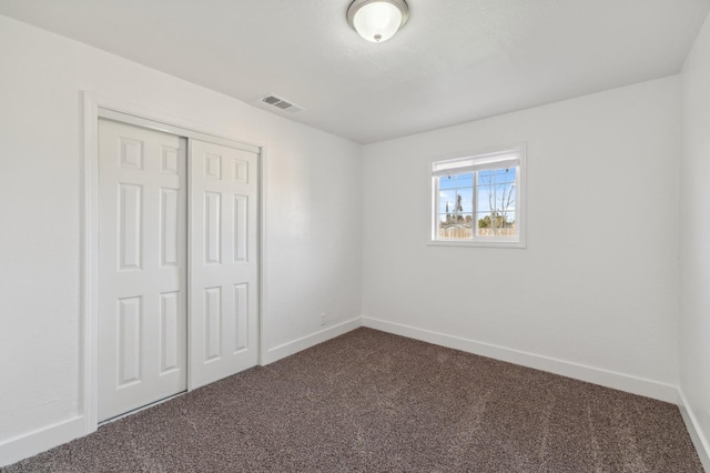 unfurnished bedroom with dark colored carpet and a closet