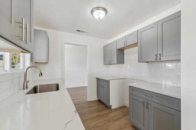 kitchen featuring sink, gray cabinetry, and light stone counters