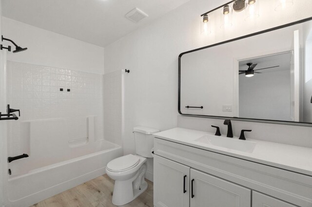 full bathroom with hardwood / wood-style flooring, toilet,  shower combination, ceiling fan, and vanity