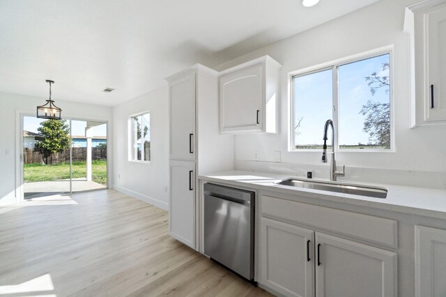 kitchen with sink, light wood-type flooring, white cabinetry, dishwasher, and decorative light fixtures