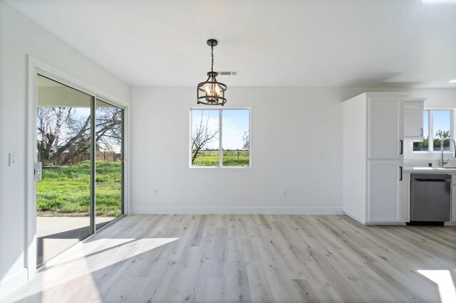 unfurnished dining area featuring sink, an inviting chandelier, and light hardwood / wood-style floors