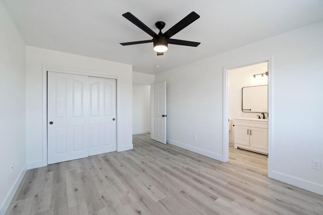 unfurnished bedroom featuring ensuite bathroom, light hardwood / wood-style flooring, ceiling fan, and a closet