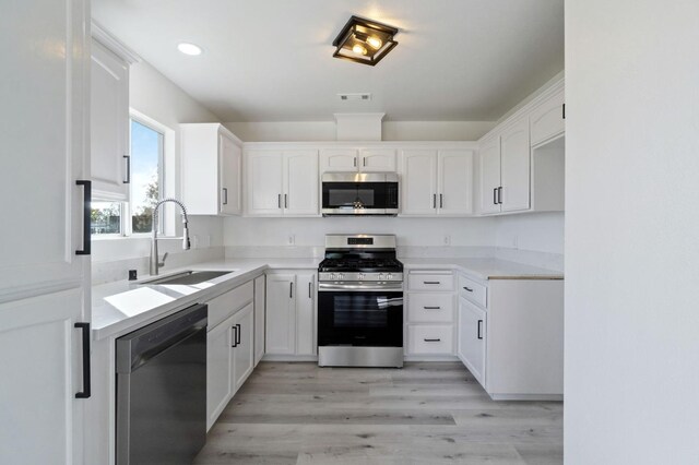 kitchen featuring light hardwood / wood-style floors, white cabinetry, stainless steel appliances, and sink