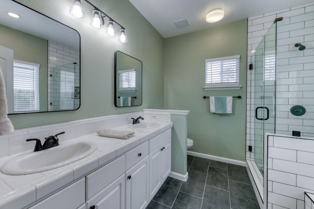 bathroom with toilet, tile patterned flooring, a shower with shower door, and a wealth of natural light