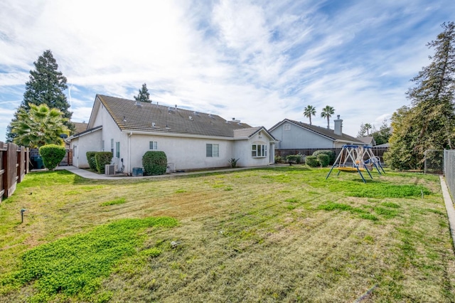 rear view of property with a playground and a yard