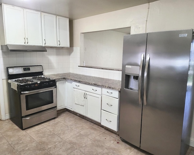 kitchen with appliances with stainless steel finishes, dark stone counters, backsplash, light tile patterned floors, and white cabinetry