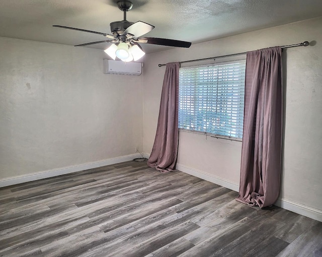 unfurnished room with a textured ceiling, ceiling fan, a wall mounted air conditioner, and dark hardwood / wood-style flooring