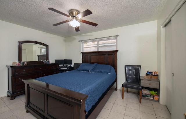 tiled bedroom featuring ceiling fan, a textured ceiling, and a closet