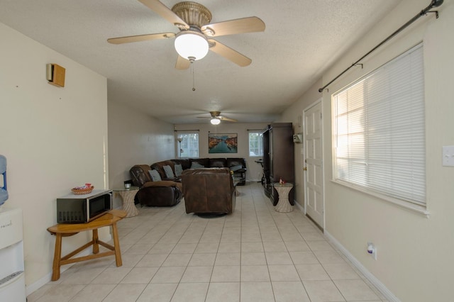 tiled living room with ceiling fan, a textured ceiling, and a healthy amount of sunlight