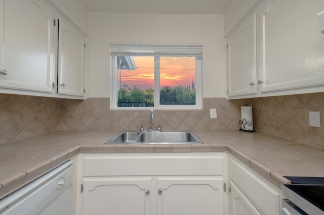 kitchen with sink, tile countertops, white cabinets, and white dishwasher