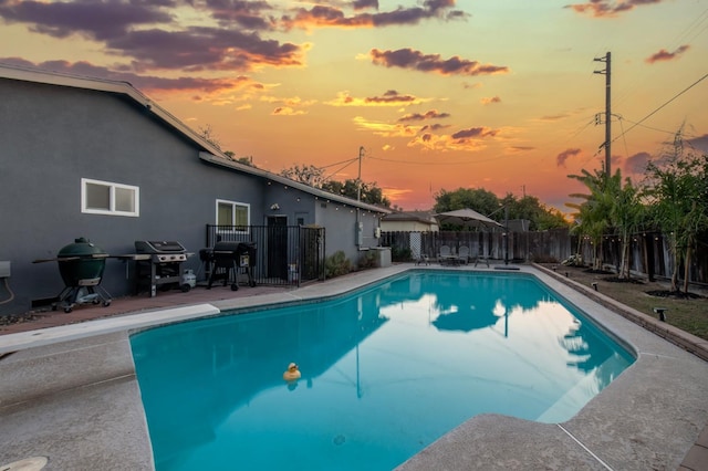 pool at dusk featuring area for grilling