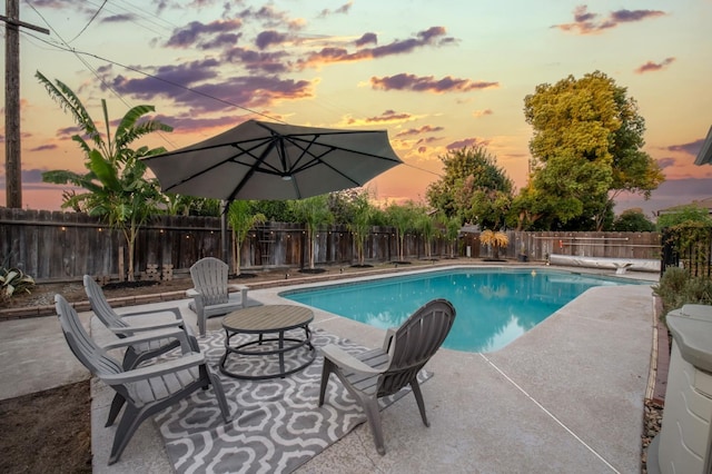 pool at dusk featuring a patio