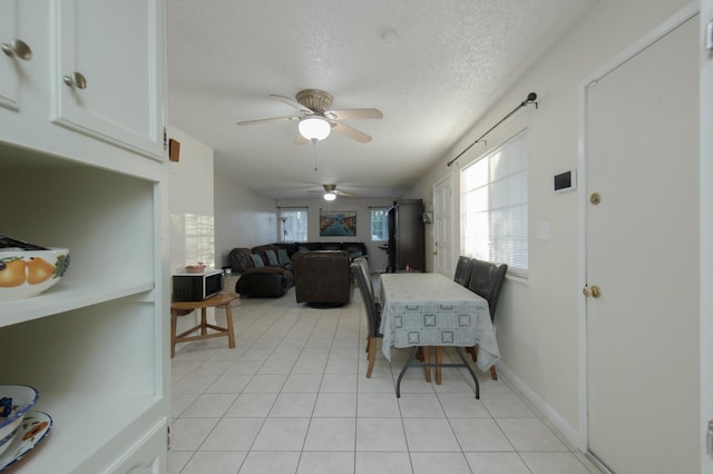 tiled dining area with ceiling fan and a textured ceiling