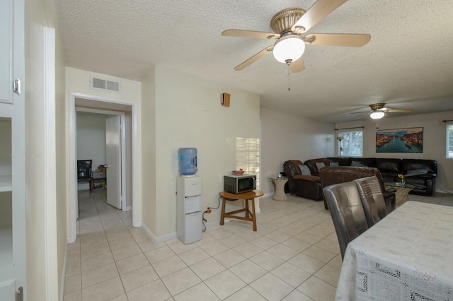 dining space featuring ceiling fan, light tile patterned floors, and a textured ceiling