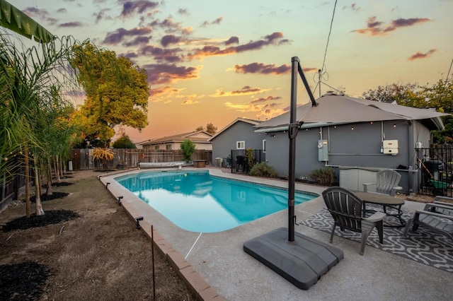 pool at dusk featuring a patio area