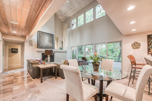 dining space featuring a towering ceiling and wooden ceiling