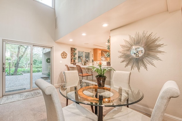 carpeted dining area featuring a towering ceiling