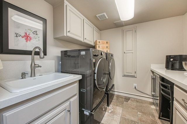 clothes washing area featuring sink, cabinets, and independent washer and dryer