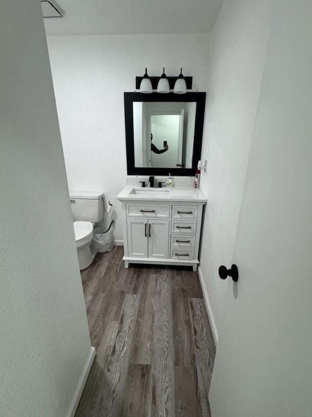 bathroom featuring toilet, vanity, and wood-type flooring