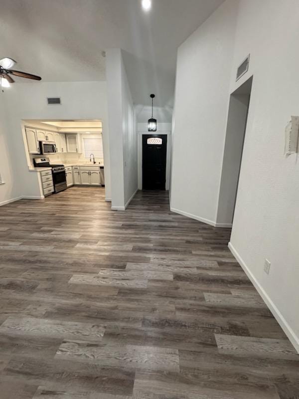 unfurnished living room with dark hardwood / wood-style flooring, ceiling fan, and sink