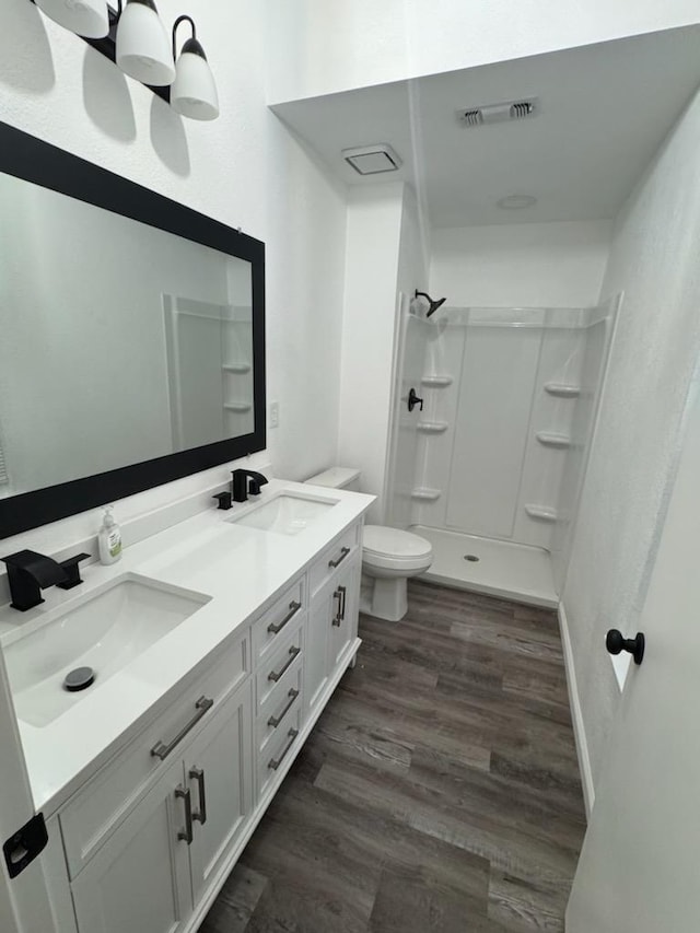 bathroom featuring a shower, toilet, vanity, and hardwood / wood-style floors