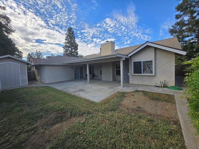 rear view of house with a shed, a patio, and a yard