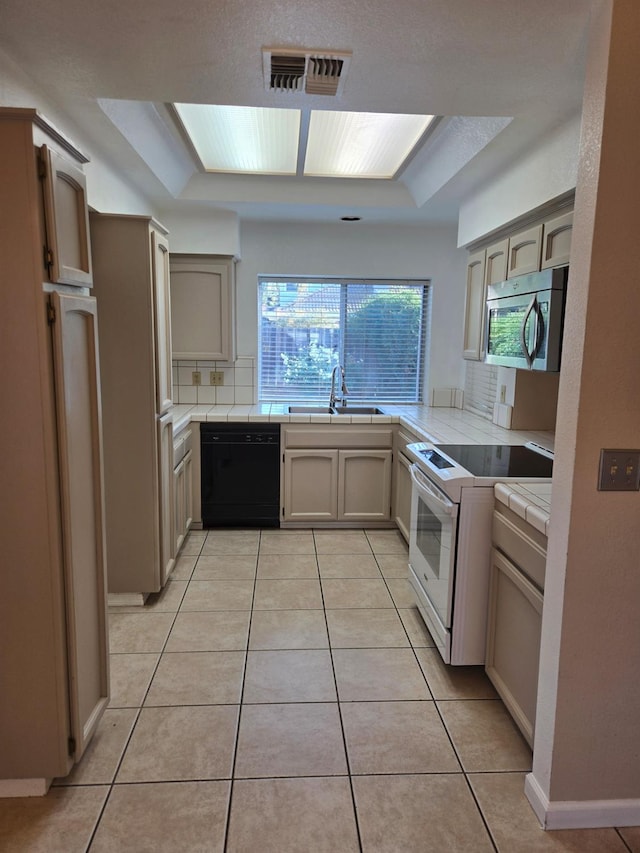 kitchen with white electric range, tile counters, light tile patterned floors, sink, and black dishwasher