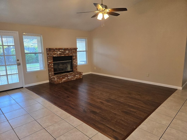 unfurnished living room featuring lofted ceiling, a brick fireplace, ceiling fan, and light tile patterned floors