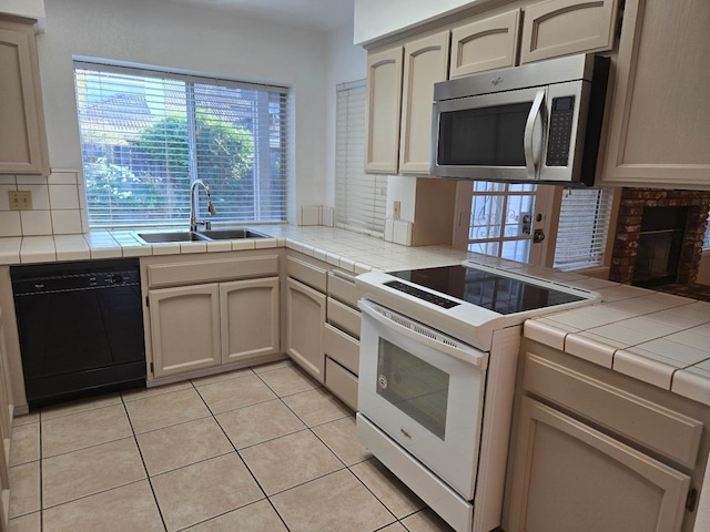 kitchen with sink, white electric stove, black dishwasher, and tile counters