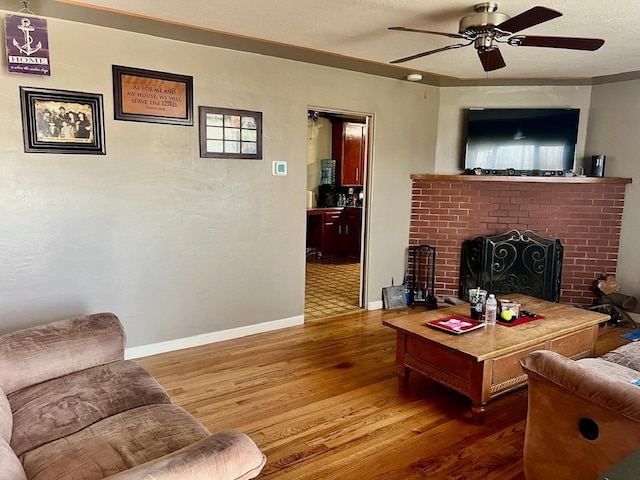 living room featuring a fireplace, a textured ceiling, ceiling fan, and wood-type flooring