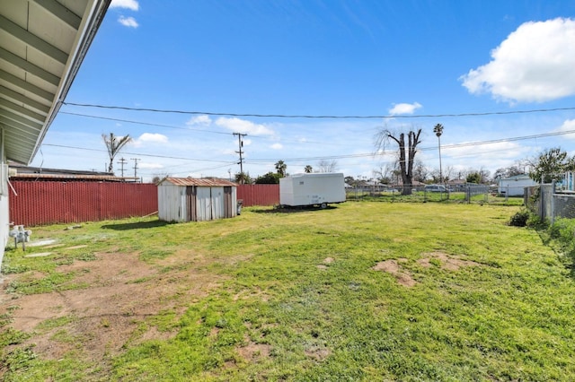 view of yard with a fenced backyard, a storage unit, and an outbuilding