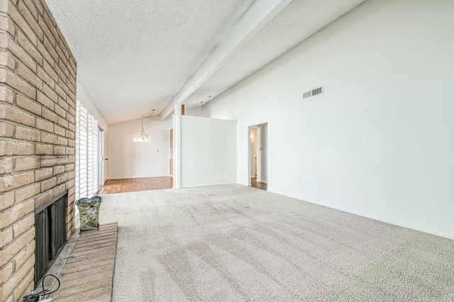 unfurnished living room with vaulted ceiling with beams, a textured ceiling, a fireplace, an inviting chandelier, and light colored carpet