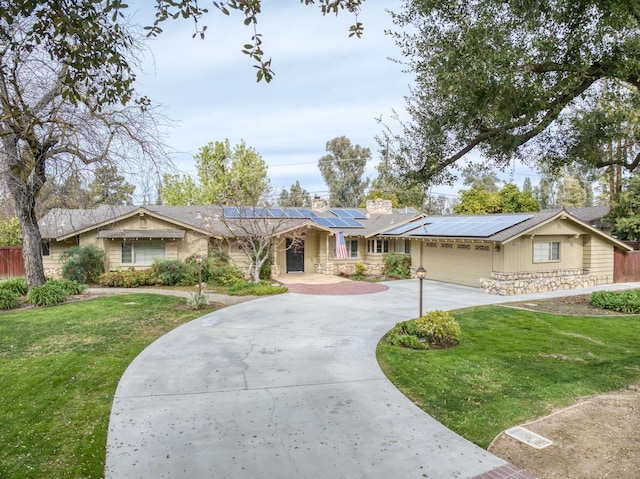 ranch-style house featuring a front lawn, solar panels, and a garage